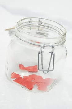 Red  paper hearts in a jar on a snow winter background.