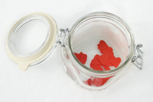 Red  paper hearts in a jar on a snow winter background.