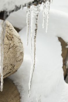 Icicles on a outdoor bench covered with snow and ice.