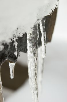 Icicles on a outdoor bench covered with snow and ice.