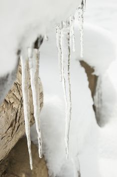 Icicles on a outdoor bench covered with snow and ice.