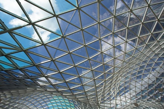 Blue roof in modern building made of glass and steel with the sky in the background, Warsaw, Poland.