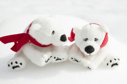 Toy teddy bears with red scarfs sitting in the snow.