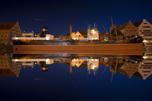 Mirror view of the Soldek at night in the river Motlawa, famous ship in the old port of Gdansk.