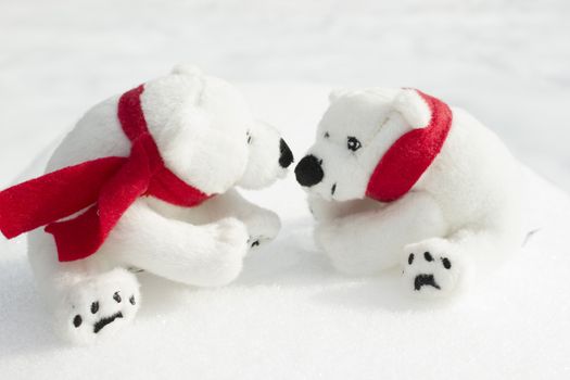 Toy teddy bears with red scarfs sitting in the snow.