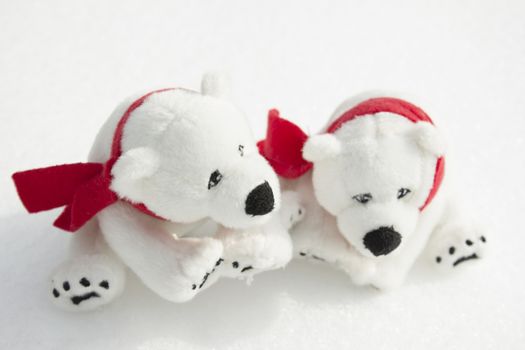 Toy teddy bears with red scarfs sitting in the snow.