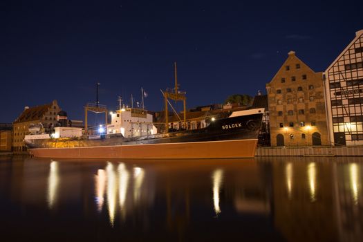 Mirror view of the Soldek at night in the river Motlawa, famous ship in the old port of Gdansk.