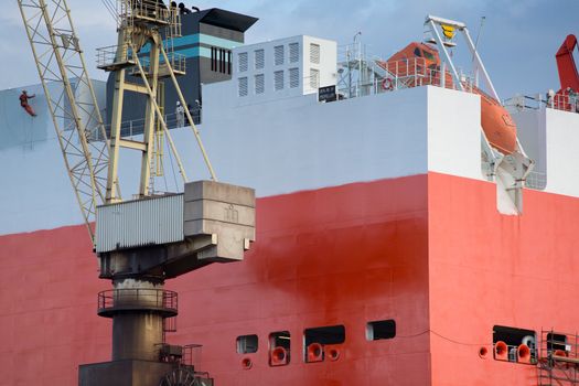 shipyard worker painting a ship under construction on drydock in Gdansk Shipyard.