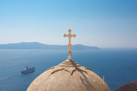 Passing cruise-boat on the aegean sea and Beautiful ornamented orthodox cross and dome.  There are many small churches all over Santorini and some larger churches in each of the major villages, Greece, 2013.