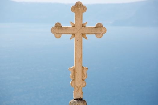 Close up from Orthodox Cross on the beautiful Blue and white rooftops of a orthodox church, in the blurred background you see the peaceful  aegean sea.  There are many small churches all over Santorini and some larger churches in each of the major villages ..Greece, 2013.