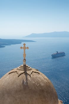 Passing cruise-boat on the aegean sea and Beautiful ornamented orthodox cross and dome.  There are many small churches all over Santorini and some larger churches in each of the major villages ..Greece, 2013.