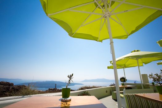 Green umbrellas and peaceful sea and little island of Santorini, greece 2013.