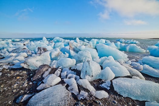 Beautiful beach in the South of Iceland with a black lava sand is full of icebergs from glaciers not far away.