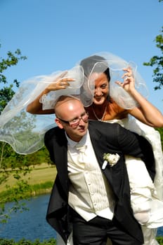 Groom is lifting his bride up in a park.