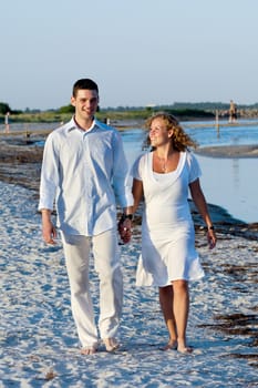 A young happy couple is walking on a beach.