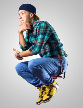 Young man dancer jumping, on a gray background