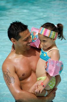 Happy man and child in pool. The mand is smiling and holding his child.