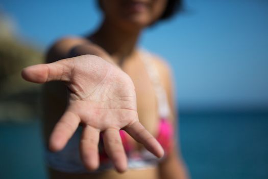 Unidentified woman showing the palm of her hand  at the beach in the harbor on the aegean sea in folegandros, Greece, 2013.