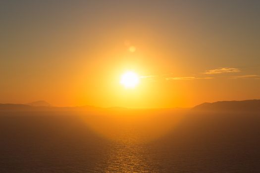 Beautiful view of the shoreline at sunset, the aegean sea, the rocky mountains and in the distance a typical white habitat of Folegandros, an amazing island from Greece 2013.