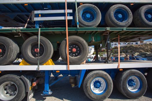 FOLEGANDROS, GREECE, JULY 24: close up of Two trucks parked on a third one and some unrecognizable people in the background at the hadbour of Folegandros, Greece 2013.