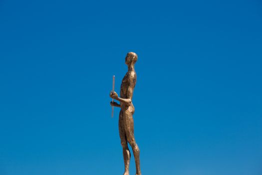 Statue made of bronze of a naked man in the blue sky of santorini, Greece 2013.