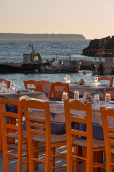 Oia fisher port restaurant and fisher boats in the background, Santorini, Greece.