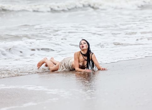 Beautiful young seminude woman in the cold sea waves