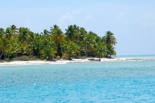 Caribbean island with a nice beach and green palms. The picture of the beach is taken from a boat on sea.