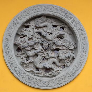 Ornamented window with dragon on a yellow wall of a temple in Hanghzou, China, 2013