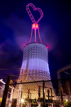 Illustration of a power plant with an illuminated love shape sign on top of it.