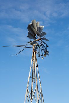 Windmill on a farm in France with blue sky in the background and wild nature around