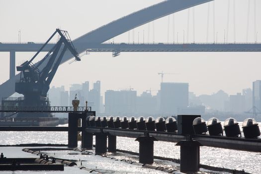 View of a massive bridge and the Shanghai harbor over the Huangpu River in Shanghai with buildings under construction in the background, China 2013