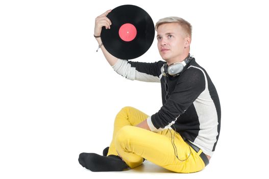 Young man with vinyl record sitting on the floor