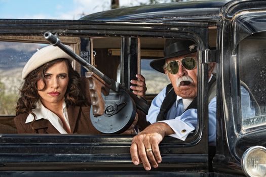 Pair of 1920s vintage gangsters waiting inside an antique car