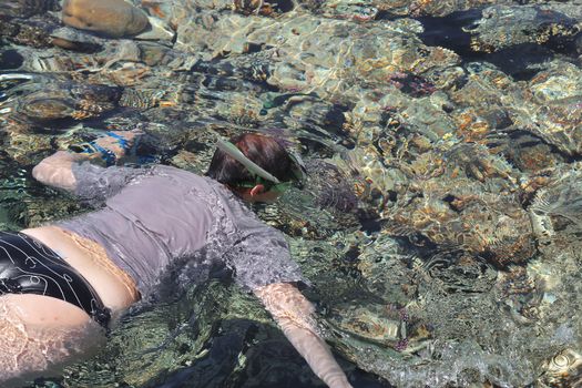 Woman photographer diving into water of Red sea