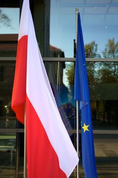 Europe and Polish Flags floating in a European conference in Poland with windows in the background