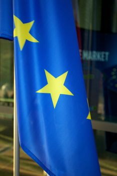 Europe and Polish Flags floating in a European conference in Poland with windows in the background