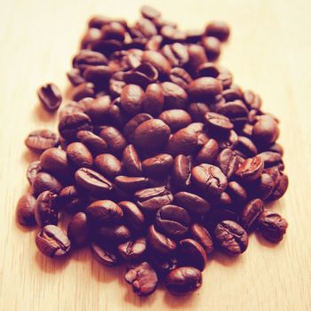 Coffee beans on wooden background with retro filter effect
