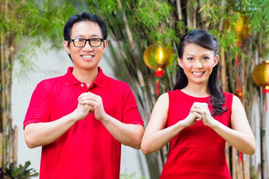 Couple celebrating Chinese new year traditional greeting, wearing red