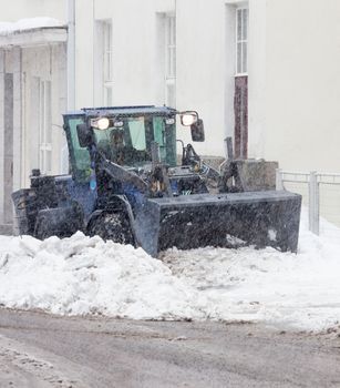 Snowplow cleaning a city street in snowfall