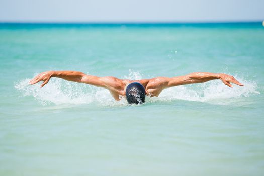 Dynamic and fit swimmer man swimming the butterfly stroke in ocean