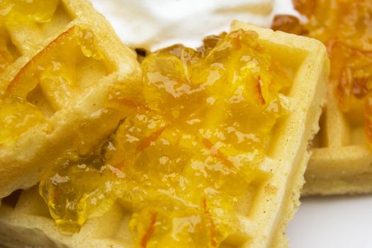 Toasted waffles with orange jam and cream on top.