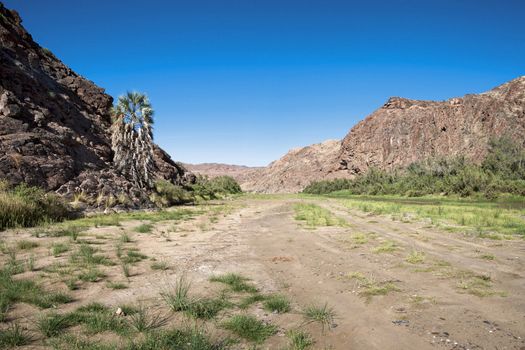 Kaokoland game reserve in Namibia, sand track going toward the Skeleton Coast Desert with a blue sky