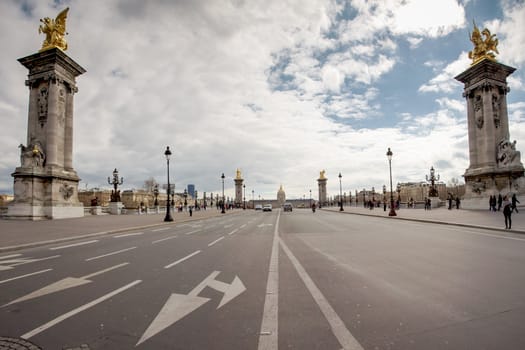 PARIS, FRANCE, MARCH 27: Empty street and Alexandre the third bridge with a view on the Invalides in Paris. A few unrecognizable people in the background.