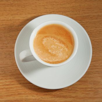 Coffee in a white cup, over wooden table