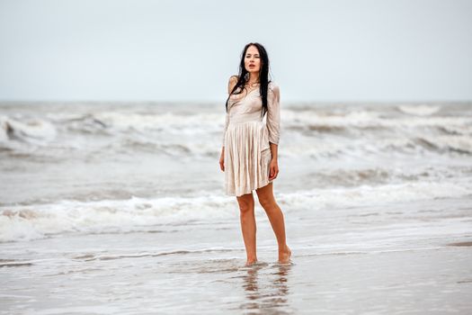 Beautiful young seminude woman in the cold sea waves