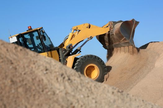 Bulldozer dumping stone and sand in a mining quarry