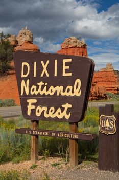 Dixie National Forest sign along the road. In the background a beautiful red rock formation