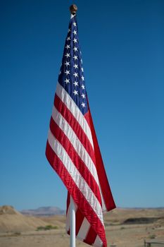 Flag on Flag Pole with blue sky and the desert of Utah in the background