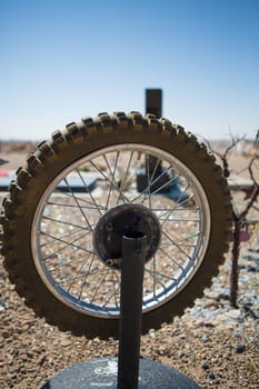 Art installation in the desert of Utah (USA). Motorcycle wheel on a stalk in a cemetery with a blue sky in the background.